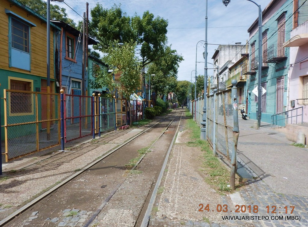 Atravesse o trilho. Vire à direita na calçada cercada pelas telas de barras coloridas que estão à esquerda, e logo após a casa verde está o Restaurante.